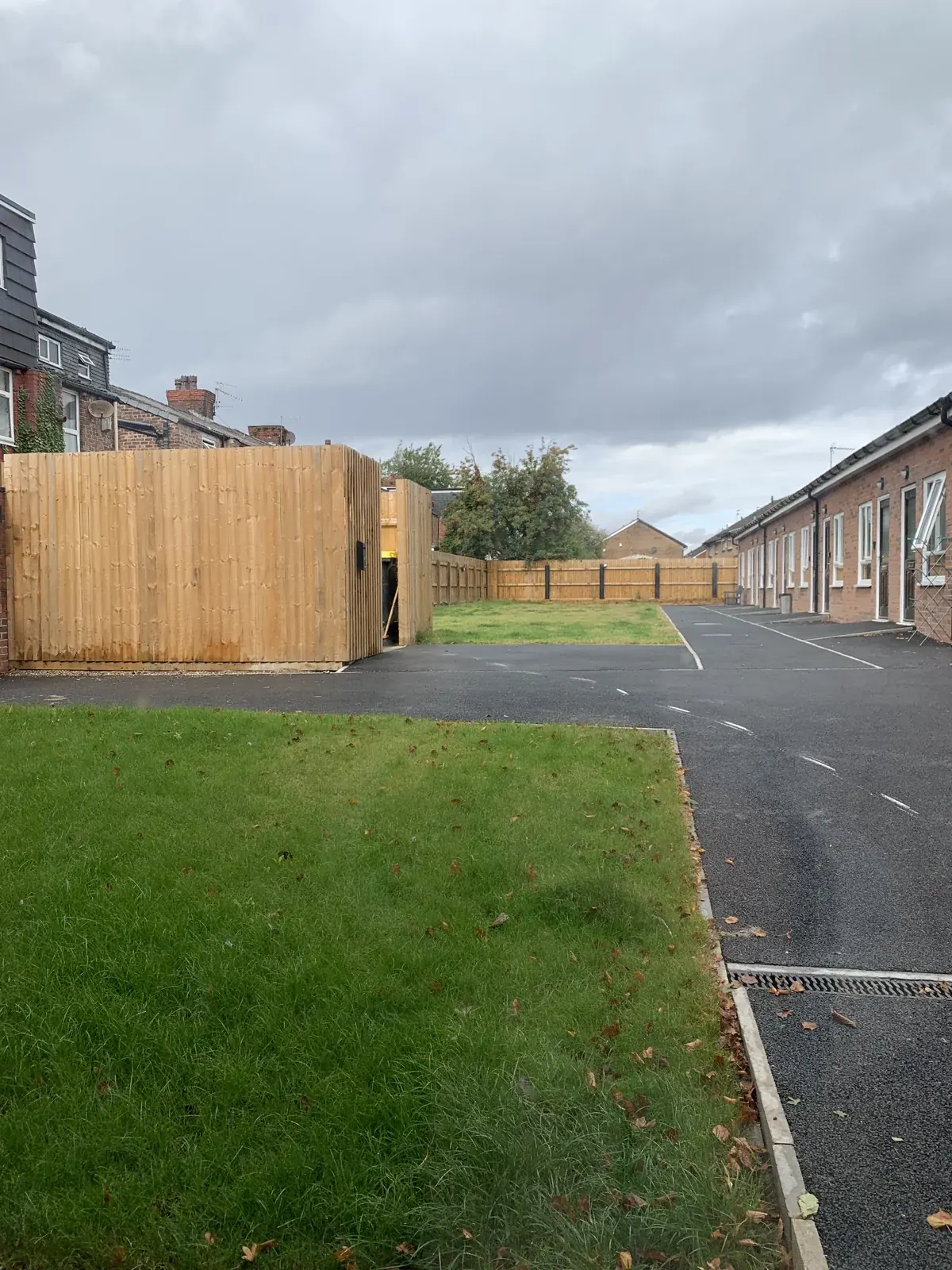 Paths, fencing and shared grounds beside a row of brick buildings.